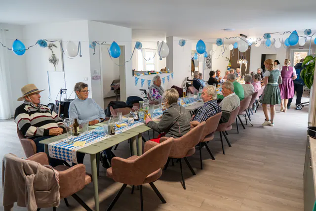 Bewohner und Team beim Oktoberfest an einer langen Tafel
